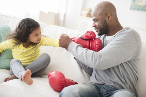 Father helping daughter with boxing gloves
