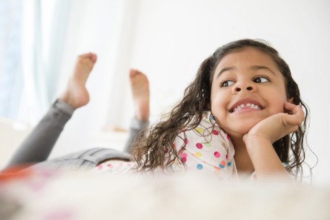 Smiling Mixed Race girl laying on bed