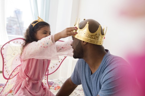 Daughter wearing costume placing crown on father
