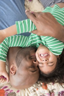 Father kissing daughter on bed