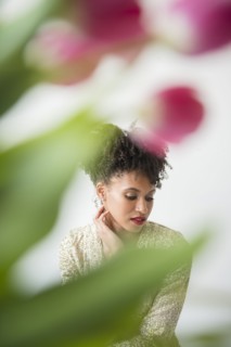 Pensive glamorous Black woman behind flowers