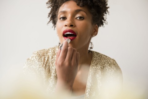 Glamorous Black woman applying red lipstick