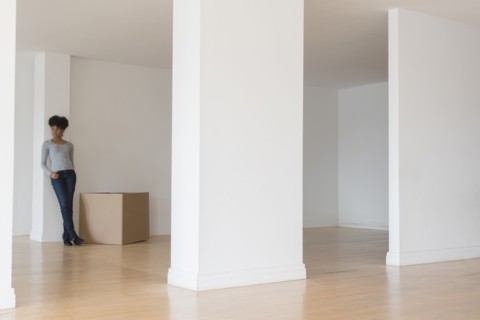 Black woman leaning on pillar in empty apartment