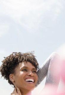 Smiling Black woman rubbing neck outdoors