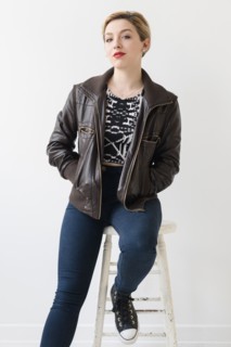 Caucasian woman wearing leather jacket sitting on stool