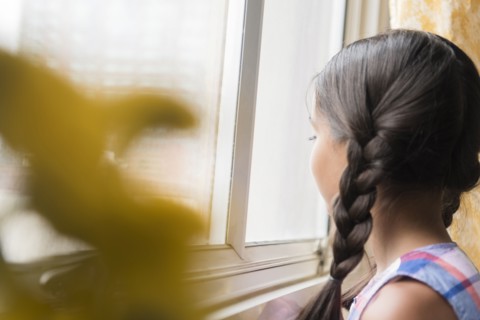 Mixed Race girl looking out window