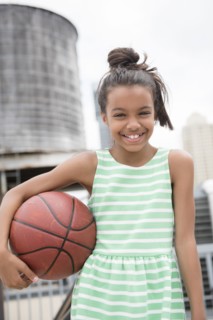 Mixed Race girl holding basketball in city
