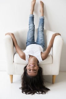 Mixed Race girl laying upside-down on armchair