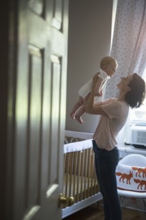 Caucasian mother holding baby son face to face in bedroom