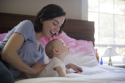 Caucasian mother and baby son laying on bed
