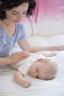 Caucasian mother and baby son laying on bed
