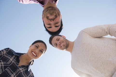 Smiling friends losing under blue sky