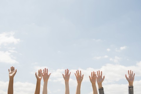 Raised hands of women outdoors