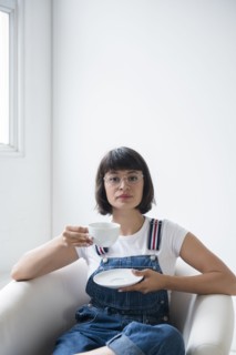 Portrait of Hispanic woman drinking coffee in armchair