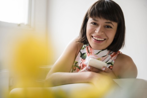 Portrait of smiling Hispanic woman holding cell phone