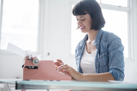 Hispanic woman typing on pink typewriter