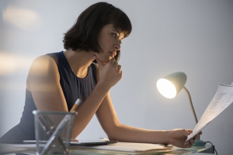 Hispanic businesswoman working late reading paperwork