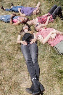 Friends relaxing in sunny grass field