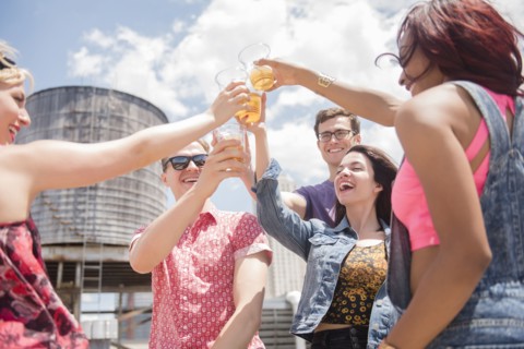 Smiling friends toasting with beer outdoors