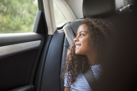 Smiling Hispanic girl in car looking out window