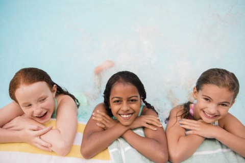 Smiling girls posing at the edge of swimming pool