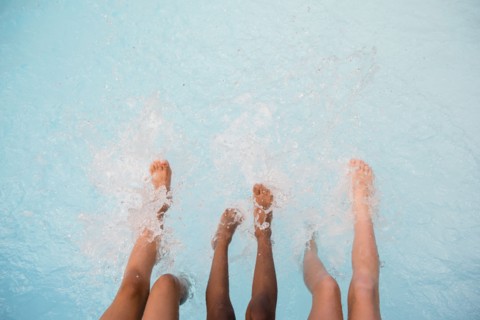 Legs of girls splashing feet in swimming pool