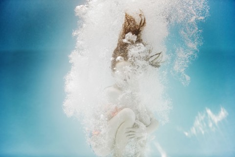 Caucasian girl swimming underwater holding nose