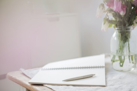 Pen on open blank notebook near flowers