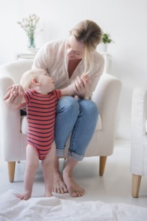 Caucasian mother helping standing baby son