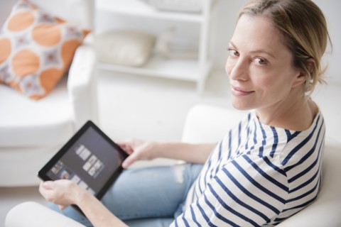 Caucasian woman sitting in armchair using digital tablet