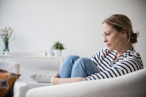 Caucasian woman sitting in armchair holding legs