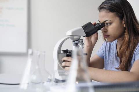 Hispanic woman using microscope