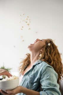 Caucasian woman throwing popcorn into mouth