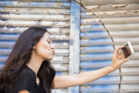 Thai woman puckering for cell phone selfie