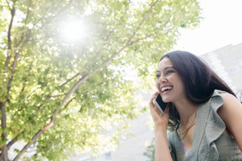 Thai woman talking on cell phone under tree