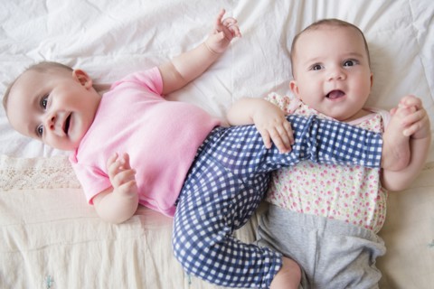 Caucasian twin baby girls playing on bed