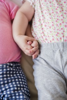 Caucasian twin baby girls holding hands