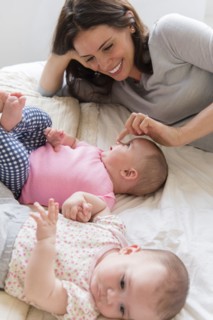 Caucasian mother touching nose of baby daughter on bed