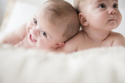 Caucasian twin baby girls laying on bed