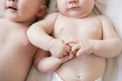 Caucasian twin baby girls holding hands