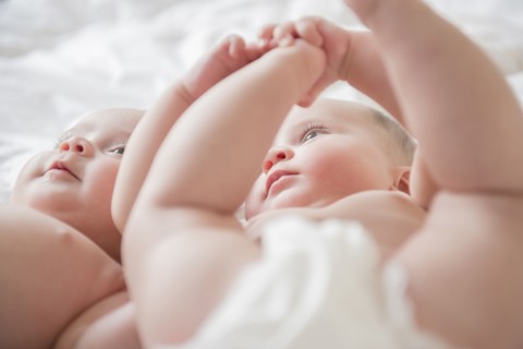 Caucasian twin baby girls laying on bed