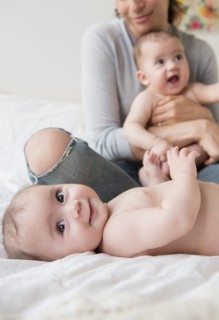 Caucasian mother with twin baby daughters on bed
