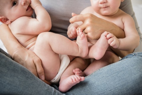 Caucasian mother holding twin baby daughters in lap