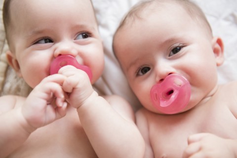 Caucasian twin baby girls sucking pacifiers