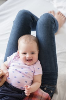 Caucasian baby girl laying on legs of mother
