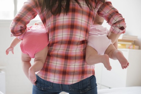Caucasian mother holding twin baby daughters