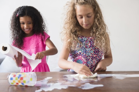 Girls cleaning spilled milk on table