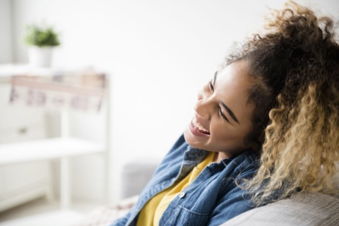 Mixed Race woman laughing on sofa