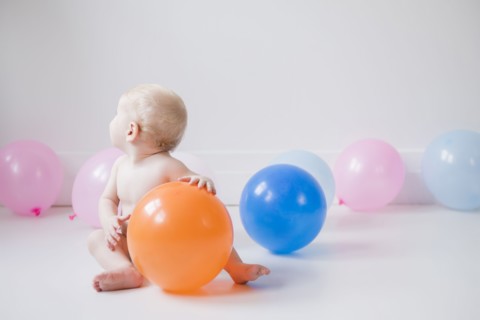 Caucasian baby boy sitting on floor with balloons