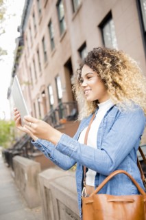 Mixed Race woman in city posing for selfie using digital tablet